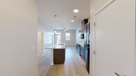 Located at 501 4th Ave SE in Cedar Rapids, Iowa, this thoughtfully designed two-bedroom, two-bathroom residence offers a clean, modern aesthetic across a single-level floor plan. Light wood-style flooring runs throughout the space, complementing the bright, neutral palette of the walls and trim.

The open-concept kitchen serves as the centerpiece of the main living area, featuring a large granite-topped island with an integrated sink and pendant lighting above. Rich, dark-stained cabinetry extends to the ceiling, providing generous storage, while black appliances—including a range, microwave, and refrigerator—complete the functional and stylish design. The kitchen flows seamlessly into the living area, which is outfitted with a ceiling fan and illuminated by recessed lighting.

Both bedrooms are well-proportioned and bright, finished with the same light flooring and neutral walls. The primary bedroom includes access to a dedicated bathroom and a closet, and features a ceiling fan. The second bedroom benefits from a large window with views of the surrounding neighborhood. Each bathroom is finished with tile flooring, dark vanity cabinetry, and white countertops. One bathroom offers a walk-in shower, while the other includes a full soaking tub and shower combination.