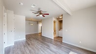 This single-story, 2-bedroom, 2-bathroom home offers a comfortable and functional layout with modern finishes throughout. The open living area features warm-toned hardwood-style flooring, neutral walls, and a ceiling fan with light fixture, creating a bright and welcoming atmosphere. A decorative chandelier adds a touch of elegance at the dining end, which flows seamlessly into the kitchen. The kitchen is well-equipped with white shaker-style cabinetry, granite countertops, a stainless steel sink, and stainless steel appliances, including a dishwasher and range. A window above the sink allows for natural light. Both bedrooms are carpeted and include ceiling fans; each room is accented by natural light from windows with blinds. The primary bedroom is generously sized and features a walk-in closet with built-in shelving rods for ample storage. The bathrooms include tile flooring, granite-topped vanities, and a glass-enclosed shower. A dedicated in-unit laundry area houses a full-size washer and dryer behind louvered doors, adding everyday convenience. Two closets throughout the home provide additional storage. The overall design is clean, neutral, and move-in ready.