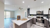 Located in the heart of Los Angeles, this well-appointed 3-bedroom, 3-bathroom residence offers a thoughtfully designed single-floor layout with modern finishes throughout. Light-toned luxury vinyl plank flooring runs seamlessly across the living spaces, complementing the clean, contemporary aesthetic.

The open-concept kitchen is a standout feature, showcasing two-tone cabinetry with dark lower cabinets and high-gloss white upper cabinets, a white quartz peninsula with a stainless steel sink, and a full suite of stainless steel appliances including a range, microwave, dishwasher, and refrigerator. Recessed lighting and a dark accent wall add depth and a modern edge to the space, which flows naturally into the living area.

The living room is generously proportioned, featuring built-in lower cabinetry with open shelving above and sliding glass doors leading to a private balcony with views of the surrounding neighborhood. A ceiling fan adds comfort to the space.

Each bedroom is bright and well-sized, with large windows fitted with vertical blinds that invite natural light. The spacious primary bedroom offers ample room for furnishings. The bathrooms are finished in clean white tile, featuring a soaking tub-shower combination with brushed gold fixtures and a floating vanity with white countertop. Four closets and a dedicated utility room provide excellent storage throughout.
