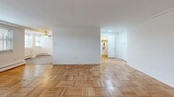 This two-bedroom, two-bathroom residence in Wynnewood, PA offers a well-organized single-floor layout with a comfortable and functional flow throughout. Classic parquet wood flooring is found throughout the main living areas and bedrooms, lending warmth and timeless character to the space.

The open living and dining area is generously sized, bathed in natural light from multiple windows dressed with blinds, and features crown molding and baseboard heating. A ceiling fan adds to the comfort of the space.

The kitchen stands out with rich, dark-stained cabinetry, white quartz countertops, a white subway tile backsplash, and a full suite of stainless steel appliances including a refrigerator, electric range, and dishwasher. Light tile flooring and recessed ceiling lighting complete the polished look.

The spacious primary bedroom features large windows with outdoor views, parquet flooring, and a sliding closet. The second bedroom is similarly well-proportioned with a window and parquet floors. Both bedrooms are bright and comfortable.

The two bathrooms are cleanly finished with white tile floors and walls. One features a soaking tub with a tiled surround, while the other offers a glass-door walk-in shower with an accent tile border. Both include vanities with ample storage.