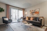 This single-floor residence offers a thoughtfully designed layout that balances comfort and functionality across its key living spaces. The living room serves as the heart of the home, highlighted by large sliding glass doors that flood the space with natural light and provide access to an outdoor area. Wood-style flooring runs throughout, complementing the neutral wall tones and textured ceilings found across the unit.

The kitchen is efficiently arranged with white cabinetry featuring black hardware, a tile backsplash, and black appliances including a refrigerator, electric range, and microwave. Light wood-style flooring and recessed lighting keep the space bright and practical.

Both bedrooms are generously sized, each featuring wood-style flooring, large windows dressed with curtain panels, and ample closet storage. The primary bedroom benefits from dual closets, offering exceptional storage capacity. Each room maintains a calm, neutral palette that creates a restful atmosphere.

The two bathrooms are clean and functional, each featuring a shower-tub combination, vanity with sink, and wood-style flooring. A hallway with interior storage connects the main living areas to the private quarters, completing this well-organized and inviting single-floor home.