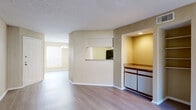 This single-floor residence offers a thoughtfully designed layout that balances open communal spaces with private retreats. The living room serves as the heart of the unit, featuring warm-toned wood-look flooring, a textured ceiling, and a full-width sliding glass door fitted with vertical blinds that floods the space with natural light and provides access to an outdoor area. Adjacent to the living room, a dedicated dining area is highlighted by a elegant chandelier and a large window.

The kitchen is accessible via a convenient pass-through window and a separate entry, and is outfitted with ample white cabinetry framed in warm wood tones, speckled laminate countertops, a black electric range, and a built-in microwave. A recessed-lit counter nook provides additional prep or storage space just outside the kitchen.

The bedrooms are generously sized, each featuring the same wood-look flooring, neutral warm-beige walls, and ceiling fans with light fixtures. Large windows dressed with horizontal blinds invite natural light and outdoor views into each room. Sliding closet doors offer practical storage solutions.

The bathroom presents a clean, functional layout with a wood-toned vanity, speckled countertops, a wide mirror, and a tiled shower-tub combination. Throughout the unit, consistent finishes and a neutral color palette create a cohesive and inviting atmosphere.
