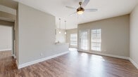 Located at 4126 Scone St in Houston, TX, this single-story home presents a clean, modern interior with a cohesive neutral color palette and wood-style flooring carried throughout every room. The open-concept living and dining area is bright and airy, benefiting from abundant natural light streaming through large windows with blinds and a set of French doors that provide direct outdoor access. A ceiling fan with a light fixture anchors the space, adding both function and subtle style.

The kitchen runs parallel to the living area and features white shaker-style cabinetry, granite countertops, a stainless steel sink, and stainless steel appliances including a refrigerator and range. A peninsula with pendant lighting overhead creates a natural transition between the kitchen and living space.

The bedrooms are generously proportioned, each equipped with ceiling fans, wood-style flooring, and ample natural light from windows with blinds. One bedroom includes a sliding glass door opening to an outdoor area with exterior views.

The bathroom showcases white cabinetry with brushed nickel hardware, granite countertops, and a large mirror above the vanity. A hallway connects the bedrooms to the bathroom and provides access to closet storage, completing the practical and well-organized layout of this home.