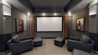 Located at 5199 Edwards Farms Rd in Hilliard, Ohio, this single-floor space is highlighted by a thoughtfully designed home theater room that delivers an immersive cinematic experience. The theater is anchored by a large, centrally mounted projection screen framed by floor-to-ceiling golden drape panels, lending a classic movie-house aesthetic to the room. A custom valance above the screen adds an architectural finishing touch, while built-in recessed speakers flanking the screen ensure high-quality audio performance.

The ceiling features a tray-style design finished in deep charcoal tones, contributing to the room's light-controlled, theater-like atmosphere. Recessed lighting is strategically placed to provide ambient illumination without detracting from the viewing experience. The flooring is covered in a neutral checkered carpet that adds texture and visual interest underfoot while also aiding in sound absorption.

Seating consists of dark leather chairs paired with matching leather ottomans, arranged to optimize sightlines to the screen. The overall color palette — combining slate gray walls, dark ceiling tones, and warm gold drapery accents — creates a sophisticated, intimate ambiance well-suited for private screenings and entertainment.
