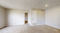 This efficient single-floor unit offers a thoughtfully organized layout across one bedroom and one bathroom. The open-concept kitchen and living area forms the heart of the home, with hard-surface flooring in the kitchen giving way to plush wall-to-wall carpeting in the living and bedroom spaces. Neutral, light gray walls throughout create a clean and cohesive aesthetic, complemented by textured ceilings and crisp white trim.

The living room is generously proportioned for the overall footprint of the unit, featuring recessed lighting and a clear sightline into the adjoining kitchen, which is equipped with cabinetry and standard appliances. The space flows naturally, making it well-suited for both relaxing and entertaining.

The bedroom is a comfortable, well-sized retreat featuring large windows that invite abundant natural light and provide views of the surrounding neighborhood. The carpeted floor and neutral tones contribute to a calm, restful atmosphere. A closet with a dedicated door adds practical storage.

The bathroom is clean and functional, featuring a full tub and shower combination with white tile surround, alongside wood-look vinyl flooring that adds a warm contrast. HVAC vents are present throughout, ensuring year-round climate control. Overall, the unit presents a move-in-ready, no-frills space ideal for those seeking straightforward, comfortable living.
