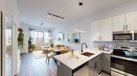 Located at 340 S Market St in Wilmington, Delaware, this thoughtfully designed one-bedroom, one-bathroom unit offers an efficient and well-appointed single-floor layout. The open-concept living, dining, and kitchen area serves as the heart of the unit, where wood-look flooring, track lighting, and large windows combine to create a bright and welcoming atmosphere. The kitchen is a standout feature, equipped with stainless steel appliances, two-tone cabinetry pairing white upper cabinets with gray lower cabinets, quartz countertops, a tile backsplash, and a peninsula with seating — ideal for both cooking and casual dining. The dining area flows naturally into the living room, which benefits from generous natural light through oversized windows. Two dedicated office spaces provide flexible options for remote work or additional storage. The bedroom features a walk-in closet, large window with outdoor views, and a bold accent wall. The full bathroom includes wood-look flooring, a vanity with dark hardware, and a glass-enclosed tub and shower combination. The unit's modern aesthetic is consistent throughout, with clean lines and contemporary finishes defining every room.
