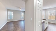 Located in Millington, Tennessee, this single-story 2-bedroom, 2-bathroom residence offers a well-designed layout with functional living spaces throughout. The open-concept living room features rich wood-style plank flooring, a textured ceiling with a ceiling fan, and multiple windows alongside a sliding glass door that fills the space with natural light and provides direct outdoor access. The kitchen is thoughtfully appointed with white shaker-style cabinetry, granite countertops, a subway tile backsplash, stainless steel appliances including a range, microwave, and refrigerator, and matching wood-style flooring. A dedicated dining area sits adjacent to the kitchen, bathed in natural light from large windows. Both bedrooms are carpeted and feature windows with blinds, offering a comfortable and quiet retreat. The primary bedroom connects to its own bathroom, which includes a granite-top vanity with an undermount sink and white cabinetry. The second bathroom features a full tub-shower combination. A hallway with a closet provides additional storage. Neutral gray walls and clean white trim carry throughout the entire residence, creating a cohesive, modern aesthetic.