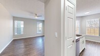 Located in Millington, Tennessee, this single-story 2-bedroom, 2-bathroom residence offers a well-designed layout with functional living spaces throughout. The open-concept living room features rich wood-style plank flooring, a textured ceiling with a ceiling fan, and multiple windows alongside a sliding glass door that fills the space with natural light and provides direct outdoor access. The kitchen is thoughtfully appointed with white shaker-style cabinetry, granite countertops, a subway tile backsplash, stainless steel appliances including a range, microwave, and refrigerator, and matching wood-style flooring. A dedicated dining area sits adjacent to the kitchen, bathed in natural light from large windows. Both bedrooms are carpeted and feature windows with blinds, offering a comfortable and quiet retreat. The primary bedroom connects to its own bathroom, which includes a granite-top vanity with an undermount sink and white cabinetry. The second bathroom features a full tub-shower combination. A hallway with a closet provides additional storage. Neutral gray walls and clean white trim carry throughout the entire residence, creating a cohesive, modern aesthetic.