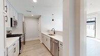Located at 282 South Ave in Fanwood, NJ, this two-story, 2-bedroom, 2-bathroom residence offers a thoughtfully designed layout spread across two well-proportioned floors. The main level hosts an open-concept living, dining, and kitchen area bathed in a clean, modern aesthetic. The kitchen is outfitted with white shaker cabinetry, quartz countertops, a subway tile backsplash, stainless steel appliances including a gas range and dishwasher, and black-accented pendant lighting that adds a contemporary touch. A pantry and ample storage provide added functionality. Light wood-tone flooring flows seamlessly throughout both floors, complementing the bright, neutral palette. The upper level features two bedrooms with vaulted ceilings, ceiling fans, and windows that bring in generous natural light. The primary bedroom is generously sized and accompanied by multiple closets with built-in shelving. Both bathrooms are finished to a high standard, with one showcasing an LED-backlit vanity mirror, a glass-enclosed tiled shower, and marble-style flooring. A versatile loft space with soaring ceilings and a sleek metal railing overlooks the upper level. Additional highlights include a private balcony, multiple utility rooms, and abundant closet space throughout.