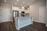 Located at 300 S Tulane Ave in Oak Ridge, Tennessee, this well-appointed single-floor residence offers a thoughtfully designed open-concept layout with modern finishes throughout. The kitchen serves as a central highlight, featuring white shaker cabinetry, granite-style countertops, a tile backsplash, and a full suite of stainless steel appliances including a refrigerator, range, microwave, and dishwasher. A kitchen island with an undermount sink and elegant pendant lighting adds both functionality and visual appeal, while soaring vaulted ceilings create an impressive sense of openness as the space flows into the living area. The living room is bright and airy, benefiting from natural light through large windows and a ceiling fan overhead. Wood-look flooring runs throughout the main living areas, while the bedrooms feature plush carpeting for added comfort. Each bedroom is generously sized with ceiling fans and natural light. The primary bathroom is equipped with a granite-topped vanity, wood-look flooring, and access to a walk-in closet. A secondary full bathroom includes a tub/shower combination, a single vanity with granite countertop, and wood-look flooring. The unit also includes a dedicated pantry closet, providing ample storage. The overall ambiance is clean, contemporary, and move-in ready.