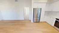 Located at 5322 Red Sage in Irvine, CA, this modern single-floor residence spans 1,320 square feet and features 3 bedrooms, 1 bathroom, and 3 closets. The open-concept kitchen and living room is anchored by a sleek, all-white kitchen outfitted with stainless steel appliances — including a French door refrigerator, gas range, built-in microwave, and dishwasher — complemented by white shaker cabinetry, light quartz countertops, and a tile backsplash. Light wood-look flooring flows throughout the main living areas, enhancing the bright, airy ambiance. The spacious living room features a large multi-pane window that fills the space with natural light. The primary bedroom measures 210 square feet and is joined by two additional bedrooms, all carpeted and naturally lit by windows with exterior views. Each bedroom benefits from dedicated walk-in closet space featuring multi-tier shelving systems with carpeted floors. The bathroom is well-appointed with a white vanity, large mirror with overhead lighting, and a glass-enclosed walk-in shower. Clean white walls and recessed lighting throughout lend the home a crisp, contemporary feel.
