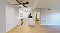 Located at 9901 Lurline Ave in the Chatsworth neighborhood of Los Angeles, this one-bedroom, two-bathroom unit offers a thoughtfully laid-out single-floor plan. Light wood-style flooring runs throughout, complementing the neutral tones of the walls and creating a bright, cohesive aesthetic.

The open living area is airy and well-lit, featuring a ceiling fan with a built-in light fixture and a textured ceiling. A sliding glass door leads to a private balcony overlooking a landscaped courtyard, with views of the surrounding multi-story building complex. Natural light flows freely through large windows and the glass door.

The galley-style kitchen is efficiently designed with crisp white cabinetry, white quartz countertops, a stainless steel sink, dishwasher, refrigerator, range, and microwave. A skylight overhead adds additional brightness to the kitchen space.

The generously sized primary bedroom features mirrored sliding closet doors that enhance the sense of space, along with a window offering views of the courtyard. A hallway connects the bedroom to the bathrooms, one of which is accessible directly from the bedroom. The unit's clean, modern finishes and functional layout make it a practical and comfortable residence in the San Fernando Valley.