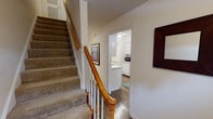 Located at 849 Jamestown Drive in Winter Park, Florida, this two-story residence offers a well-organized layout distributed across two levels, connected by a carpeted staircase with a classic wood banister. The main level features wood-style flooring throughout, lending a cohesive and clean aesthetic to the living and dining areas. The living room provides a comfortable, open feel with neutral walls and access to the kitchen through a pass-through window, creating a connected flow between spaces. A dedicated dining area accommodates a small table beneath a pendant light fixture, with a window that brings in natural light. The kitchen is outfitted with white cabinetry, light countertops, and essential appliances, maintaining a bright and functional character. A full bathroom on the main level includes a tub/shower combination, a vanity with a large mirror, and wood-style flooring. The upper level hosts the bedrooms, each featuring plush carpeting, neutral tones, and ample wall space. One bedroom includes sliding glass doors that invite natural light. The overall ambiance throughout the residence is light, airy, and neatly appointed, reflecting a casual Florida lifestyle.