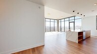 Located on Hillsboro Pike in Nashville's 37215 corridor, this single-floor residence offers four bedrooms, three bathrooms, and a thoughtfully designed open layout. The living and kitchen area is anchored by dramatic floor-to-ceiling glass walls with black metal framing, flooding the space with natural light and framing sweeping panoramic views of the Nashville skyline and surrounding mountain ridgeline. A glass door opens directly onto a balcony, extending the living space outdoors. The kitchen features a generous waterfall-edge island in white stone, warm wood cabinetry, a marble-style backsplash, stainless steel appliances, and pendant lighting. Light hardwood flooring flows throughout the main living areas, transitioning seamlessly between rooms. The bedrooms are bright and airy, with large floor-to-ceiling windows offering stunning elevated views of the city below. The primary bedroom includes access to dedicated closets with adjustable wire shelving systems. The bathrooms are finished with large-format tile flooring and glass-enclosed walk-in showers with vertically tiled walls. A well-appointed laundry room with stone countertops, a utility sink, and ample cabinetry adds everyday convenience. The overall design is clean, contemporary, and light-filled throughout.