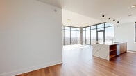 Located on Hillsboro Pike in Nashville's 37215 corridor, this single-floor residence offers four bedrooms, three bathrooms, and a thoughtfully designed open layout. The living and kitchen area is anchored by dramatic floor-to-ceiling glass walls with black metal framing, flooding the space with natural light and framing sweeping panoramic views of the Nashville skyline and surrounding mountain ridgeline. A glass door opens directly onto a balcony, extending the living space outdoors. The kitchen features a generous waterfall-edge island in white stone, warm wood cabinetry, a marble-style backsplash, stainless steel appliances, and pendant lighting. Light hardwood flooring flows throughout the main living areas, transitioning seamlessly between rooms. The bedrooms are bright and airy, with large floor-to-ceiling windows offering stunning elevated views of the city below. The primary bedroom includes access to dedicated closets with adjustable wire shelving systems. The bathrooms are finished with large-format tile flooring and glass-enclosed walk-in showers with vertically tiled walls. A well-appointed laundry room with stone countertops, a utility sink, and ample cabinetry adds everyday convenience. The overall design is clean, contemporary, and light-filled throughout.