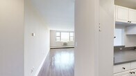This 2-bedroom, 1-bathroom residence is thoughtfully laid out across a single floor, offering a comfortable and functional living environment. The open living room serves as the heart of the home, featuring gleaming hardwood-style flooring, neutral-toned walls, and a large multi-pane window that frames scenic views of water and greenery, flooding the space with natural light. A built-in wall unit provides climate control, and baseboard heating ensures year-round comfort.

The galley-style kitchen is efficiently designed with ample white cabinetry, gray countertops, and a full suite of white appliances including a gas range, dishwasher, and refrigerator. A pass-through window connects the kitchen visually to the living area, enhancing the open feel.

The primary bedroom is generously sized, offering hardwood-style floors, a ceiling fan, a large window with serene outdoor views, and a mirrored sliding-door closet alongside an additional walk-in closet. The second bedroom is equally inviting, with similar flooring and good natural light.

The bathroom is finished with classic neutral tile surrounding the tub-shower combination, a white vanity with stone-topped countertop, and a mirrored medicine cabinet. A hallway connects all rooms, completing the efficient and well-organized floor plan.