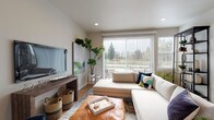 Located at 605 Ayers Rd in Eugene, Oregon, this two-story home offers a well-designed layout that balances functionality with modern style throughout both levels. The main level features an open-concept living and dining area bathed in natural light from large windows with vertical blinds that frame views of surrounding greenery. Light hardwood-style flooring flows throughout, complementing the neutral wall tones and recessed lighting that create a clean, welcoming ambiance.

The kitchen is a standout feature, showcasing white shaker cabinetry, quartz countertops, and stainless steel appliances including a range, microwave, and dishwasher. A central island provides additional prep space and casual seating. A conveniently located powder room with a pedestal sink and hardwood-style flooring serves the main level.

Upstairs, the bedrooms are finished with plush carpet and feature built-in closets with sliding doors. Each room receives natural light through well-placed windows with blinds. The upper level includes a full bathroom with a tub-shower combination, quartz vanity, and hardwood-style flooring, along with an additional full bathroom. The overall design is cohesive and move-in ready.
