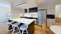 Located at 3555 Saint-Antoine O in Montreal, this well-designed 2-bedroom, 1-bathroom unit offers a clean, contemporary aesthetic throughout. Light oak hardwood flooring flows seamlessly across the single floor, complementing the crisp white walls and modern finishes found in every room.

The open-concept kitchen and dining area serves as a functional hub, featuring dark cabinetry with under-cabinet lighting, white quartz countertops, a white tile backsplash, stainless steel appliances, and a central island with bar seating. The adjacent living room is bright and inviting, with a wall-mounted mini-split system and a large window drawing in natural light.

The primary bedroom is a comfortable retreat, benefiting from floor-to-ceiling windows with outdoor views and its own mini-split unit. The second bedroom is clean and quiet with a built-in closet. A dedicated office space adds valuable flexibility to the layout.

The bathroom is finished to a high standard, with large-format white wall tiles, a glass-enclosed shower with black fixtures, a wood-tone vanity, and a round mirror. The hallway also houses a stacked in-unit washer and dryer for added convenience. Three closets provide ample storage, and a private balcony completes this thoughtfully laid-out home.