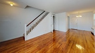 Located at 126 Litton Ave in Groton, Connecticut, this two-story townhouse at Groton Townhouses offers a well-organized layout spread across two floors. The main level features gleaming, polished hardwood floors that extend throughout the open living area, which is anchored by a classic staircase with a white balustrade and rich wood handrail. The living space is bright and open, with a welcoming entryway and easy access to additional rooms. The kitchen is thoughtfully updated, showcasing rich dark wood cabinetry, light granite countertops, a mosaic tile backsplash, stainless steel appliances including a dishwasher, and stone tile flooring. The upper level continues the hardwood flooring throughout, with multiple well-lit rooms that benefit from natural light through large windows fitted with blinds. Radiator heating units are present in the upstairs rooms, providing efficient warmth. The bedrooms offer ample space and include closet access, with clean white walls creating a neutral, versatile backdrop. The full bathroom is finished with stone tile flooring, white subway tile surrounding a soaking tub and shower, and a dark wood vanity with a white basin. The overall aesthetic is clean, classic, and functional throughout.