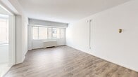 Located at 825 New Hampshire Ave NW in Washington, DC's Foggy Bottom neighborhood, Unit 205 is a thoughtfully laid-out studio offering a living area, kitchen, and full bathroom across a single floor. The living area features light-toned hardwood-style flooring and crisp white walls that create a clean, bright atmosphere. A wide window fitted with horizontal blinds allows natural light to filter in while offering views of the surrounding urban streetscape, with a radiator unit positioned beneath providing in-unit heating. The space includes a closet and entry door, contributing to practical everyday functionality. The kitchen is efficiently designed with white cabinetry, a gas range, a full-size refrigerator, a sink, and light tile flooring — maximizing utility within a compact footprint. The bathroom features classic white subway tile wainscoting along the walls, a toilet, and a vanity with a mirrored medicine cabinet, lending a timeless, clean aesthetic. Throughout the unit, the neutral color palette and consistent use of light materials contribute to an open, airy feel. The overall layout is compact yet functional, well-suited for urban living in one of Washington, DC's most walkable and centrally connected neighborhoods.