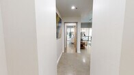 This thoughtfully designed single-story residence offers a well-appointed layout across six distinct spaces. Polished concrete floors run throughout, lending a sleek, urban aesthetic that ties the home together cohesively. The combined dining and living area is bright and open, anchored by floor-to-ceiling windows that flood the space with natural light and offer outdoor views. Track lighting overhead and carefully placed artwork add a gallery-like quality to the room. The kitchen features warm honey-toned wood cabinetry, marble-look countertops and backsplash, and stainless steel appliances, including a dishwasher and built-in microwave. The spacious primary bedroom continues the floor-to-ceiling window treatment, framing outdoor courtyard views and filling the room with natural light. A dedicated walk-in closet provides ample storage with wrap-around wire shelving. The hallway, accented with curated wall art, connects the living areas to the private quarters. The full bathroom is elegantly finished with large-format grey tile flooring, warm wood cabinetry with white countertops, a soaking tub, and louvered wood closet doors that add a refined touch to the overall design.