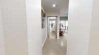 This thoughtfully designed single-story residence offers a well-appointed layout across six distinct spaces. Polished concrete floors run throughout, lending a sleek, urban aesthetic that ties the home together cohesively. The combined dining and living area is bright and open, anchored by floor-to-ceiling windows that flood the space with natural light and offer outdoor views. Track lighting overhead and carefully placed artwork add a gallery-like quality to the room. The kitchen features warm honey-toned wood cabinetry, marble-look countertops and backsplash, and stainless steel appliances, including a dishwasher and built-in microwave. The spacious primary bedroom continues the floor-to-ceiling window treatment, framing outdoor courtyard views and filling the room with natural light. A dedicated walk-in closet provides ample storage with wrap-around wire shelving. The hallway, accented with curated wall art, connects the living areas to the private quarters. The full bathroom is elegantly finished with large-format grey tile flooring, warm wood cabinetry with white countertops, a soaking tub, and louvered wood closet doors that add a refined touch to the overall design.