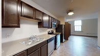 This single-floor residence offers a thoughtfully designed layout that balances functionality and comfort throughout. The galley-style kitchen is a standout feature, equipped with dark espresso cabinetry extending to the ceiling for ample storage, light countertops, and a full suite of stainless steel appliances including an electric range, over-the-range microwave, dishwasher, and refrigerator. A double-basin sink and durable tile-style flooring complete the space. An open living area adjacent to the kitchen provides a versatile gathering space with neutral-toned walls and tile flooring, while a wall-mounted air conditioning unit ensures year-round comfort. A dedicated laundry closet with a side-by-side washer and dryer adds significant convenience. The bedrooms are carpeted and filled with natural light through large windows with blinds, offering views of the surrounding cityscape. Ceiling fans with integrated lighting are present, and sliding closet doors provide practical storage. The bathrooms are finished with dark vanity cabinetry, white countertops, and tile flooring. One bathroom features a walk-in shower stall, while the other includes a soaking tub with built-in shelving. The overall design is clean, modern, and move-in ready.