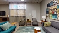 Located at 225 W Third Street in the heart of downtown Long Beach, California, this Social Lounge is a thoughtfully designed single-floor communal space that brings together comfort, functionality, and contemporary style. The open-concept layout accommodates a variety of social activities, offering distinct zones that flow seamlessly into one another.

The lounge area is anchored by a plush gray sofa and paired accent chairs arranged around teal-toned area rugs, creating an inviting conversation space. A curated gallery wall featuring bold, colorful artwork adds an artistic focal point to the room. Large windows dressed with sheer curtains allow natural light to fill the space and offer views of the surrounding urban streetscape.

At the heart of the room, a full-size pool table serves as a central entertainment feature, complemented by bar-height seating nearby for casual dining or socializing. A dedicated dining area with a live-edge table and mixed seating provides additional gathering space.

The integrated kitchen is equipped with stainless steel appliances — including a gas range, microwave, and refrigerator — alongside warm wood cabinetry and light quartz countertops, making the space well-suited for entertaining. Light hardwood flooring runs throughout, tying all areas together with a clean, modern aesthetic. Recessed panel ceilings and ample overhead lighting ensure the space remains bright and welcoming at any hour.