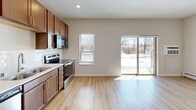 Located at 1330 High Site Dr in Eagan, MN, this one-bedroom, one-bathroom unit offers a thoughtfully designed layout across a single floor. Light-toned luxury vinyl plank flooring flows throughout the main living areas, complemented by neutral wall tones and recessed lighting that keep the space feeling bright and clean.

The open-concept living, dining, and kitchen area serves as the heart of the unit. The kitchen is well-appointed with warm-toned wood cabinetry extending to the ceiling, stainless steel appliances including a refrigerator, range, over-the-range microwave, and dishwasher, paired with a crisp white countertop and undermount sink. A window above the counter and a sliding glass patio door in the living area invite abundant natural light and outdoor views.

A hallway lined with two closets and a distinctive sliding barn door connects the main living area to the private spaces. The bedroom features plush carpeting, a closet, and a calm, neutral palette. The full bathroom offers a matching wood-toned vanity with a white countertop, a tub-shower combination, and continued hard-surface flooring. An in-unit laundry area adds everyday convenience. This unit presents a practical and modern living environment well-suited for comfortable single-occupant living.