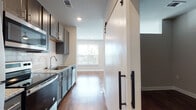 Located at 900 Owl Wood Ln in Summerville, SC, this single-floor residence showcases a thoughtfully designed open layout with modern finishes throughout. Rich hardwood flooring flows seamlessly across the living areas, complementing the neutral wall tones and crisp white trim that give the space a clean, contemporary feel.

The kitchen is a functional highlight, outfitted with gray shaker-style cabinetry, granite countertops, a classic white subway tile backsplash, and stainless steel appliances including a dishwasher, range, and microwave. A single-basin undermount sink adds a polished touch. A striking barn door with matte black hardware serves as a stylish divider, adding architectural character to the space.

The hallway connects key areas efficiently, revealing an in-unit stacked washer and dryer closet for added convenience. The main living area is bright and open, featuring a pair of large windows fitted with horizontal blinds that frame pleasant outdoor views of the surrounding community and greenery, flooding the room with natural light.

The bathroom features granite countertops consistent with the kitchen's design language, paired with hardwood-style flooring and clean, neutral walls. Recessed lighting throughout the home ensures well-distributed illumination. The overall ambiance is modern, clean, and move-in ready, reflecting quality craftsmanship in a well-appointed Summerville community.