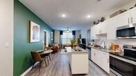 This single-floor unit offers an efficient and thoughtfully designed layout across a compact but functional footprint. The open-concept kitchen and living area serves as the heart of the space, where wood-look flooring flows continuously throughout. The kitchen is outfitted with white shaker cabinetry, granite countertops, a central island, and a full suite of stainless steel appliances including a refrigerator, range, microwave, and dishwasher. Recessed lighting illuminates the kitchen, which connects seamlessly to a dining area and living room. The living room features a striking deep-green accent wall, a ceiling fan, and a large window with blinds that draws in natural light. The bedroom is carpeted and comfortably sized, with a ceiling fan, large window, and a dedicated closet. The bathroom is finished with granite countertops, white shaker vanity cabinetry, wood-look flooring, and a full tub-shower combination with subway tile surround. Throughout the unit, consistent finishes and neutral tones create a cohesive, modern aesthetic.