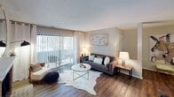 Located at 2014 Countrymens Ct in Charlotte, NC, this single-floor residence offers a thoughtfully designed layout with contemporary finishes and a cohesive, modern aesthetic throughout. The living room serves as a welcoming centerpiece, featuring rich wood-look flooring, a classic brick fireplace with a white mantle, and a sliding glass door that allows natural light to fill the space and provides access to an outdoor area. The kitchen is well-appointed with white cabinetry, black appliances including a refrigerator, electric range, and built-in microwave, complemented by a mosaic tile backsplash and a peninsula with a granite-style countertop that seats bar stools — ideal for casual dining or entertaining. Adjacent to the kitchen, the dining area makes a strong visual statement with a bold teal accent wall, a gold geometric wall sculpture, a pendant light fixture, and wood-look flooring that carries throughout. The bedroom continues the teal accent wall theme, offering a serene retreat with ample natural light and plush carpeting. The bathroom includes a full tub and shower combination. A wine shelf and dedicated hallway connect the living spaces, adding both function and character to this well-curated Charlotte residence.
