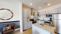 Located at 141 Stobhill Ln in Fuquay Varina, NC, this single-floor residence offers a thoughtfully designed layout with modern finishes throughout. The kitchen is a standout feature, equipped with granite countertops, gray shaker-style cabinetry, a full suite of stainless steel appliances including a range with a wall-mounted hood vent, dishwasher, refrigerator, and microwave, all centered around a convenient island for additional prep space. The living area is generously sized, featuring a two-toned accent wall, large windows that invite natural light, and ample room for comfortable seating arrangements. The bedrooms are carpeted and well-lit, with large windows offering natural light and ceiling fans for comfort. The primary bedroom includes access to a spacious walk-in closet outfitted with wire shelving and hanging rods for organized storage. Bathrooms include a primary bath with a granite-topped vanity, a glass-enclosed walk-in shower, and wood-look flooring, as well as a secondary full bath featuring a shower-tub combination. The overall design balances clean, neutral tones with warm accents, creating a cohesive and inviting living environment throughout the home.