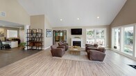 Located at 1151 Mobley Dr in Savannah, GA, this single-floor community clubhouse offers a well-appointed and inviting space designed to foster comfort and connection. The interior is finished with light wood-look flooring throughout, warm neutral walls, and soaring vaulted ceilings that lend an open, airy feel to the main gathering areas.

The central lounge is a standout feature, anchored by a classic white-mantel fireplace and a wall-mounted flat-screen TV. Plush leather seating arrangements and a rustic coffee table create a relaxed, residential atmosphere, while large windows flood the room with natural light and offer views of the surrounding outdoor amenity areas.

A bright and cheerful dining nook adjoins the lounge, boasting vaulted ceilings with a circular skylight, expansive windows on multiple walls, and direct access to an outdoor deck. This sun-drenched space provides a welcoming setting for casual gatherings.

The entry reception area features recessed lighting, a seating arrangement for guests, and an information console, offering a polished and organized welcome point. Adjacent to the entry, a dedicated office space with dark tile flooring and a workstation provides a functional workspace. A coffee station and decorative shelving complete the interior details, adding both practicality and character throughout this thoughtfully designed clubhouse.