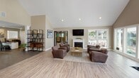 Located at 1151 Mobley Dr in Savannah, GA, this single-floor community clubhouse offers a well-appointed and inviting space designed to foster comfort and connection. The interior is finished with light wood-look flooring throughout, warm neutral walls, and soaring vaulted ceilings that lend an open, airy feel to the main gathering areas.

The central lounge is a standout feature, anchored by a classic white-mantel fireplace and a wall-mounted flat-screen TV. Plush leather seating arrangements and a rustic coffee table create a relaxed, residential atmosphere, while large windows flood the room with natural light and offer views of the surrounding outdoor amenity areas.

A bright and cheerful dining nook adjoins the lounge, boasting vaulted ceilings with a circular skylight, expansive windows on multiple walls, and direct access to an outdoor deck. This sun-drenched space provides a welcoming setting for casual gatherings.

The entry reception area features recessed lighting, a seating arrangement for guests, and an information console, offering a polished and organized welcome point. Adjacent to the entry, a dedicated office space with dark tile flooring and a workstation provides a functional workspace. A coffee station and decorative shelving complete the interior details, adding both practicality and character throughout this thoughtfully designed clubhouse.