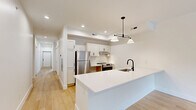 Located at 1401 Tower Grove Ave in St. Louis, MO, this 2-bedroom, 1-bathroom unit offers a thoughtfully designed single-level layout with a clean, contemporary aesthetic throughout. Light hardwood flooring flows seamlessly across every room, creating a cohesive and airy feel.

The open kitchen is well-appointed with white shaker cabinetry, light countertops, stainless steel appliances including a refrigerator, range, and dishwasher, and a sleek black-accented faucet over a single-basin sink. Pendant lighting adds a modern touch above the kitchen island, while recessed lighting illuminates the space efficiently.

The combined living and kitchen area provides a functional open-concept layout. Both bedrooms feature large windows that bring in abundant natural light and offer views of the surrounding neighborhood. Ceiling fans with integrated lighting are installed in each bedroom, enhancing comfort year-round. White panel doors with matte black hardware add a refined, modern contrast throughout.

The bathroom is finished with crisp white subway tile surrounding a full soaking tub, complemented by tile flooring and black accent hardware for a clean, minimalist look. A hallway connects the key living areas, keeping the layout practical and efficient. The overall design emphasizes simplicity, modern finishes, and comfortable livability in a compact yet well-utilized footprint.