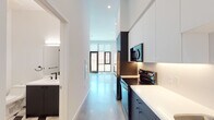 Located in the vibrant Silver Lake neighborhood of Los Angeles, this two-story residence at 1901 Blake Ave showcases a clean, contemporary design with carefully selected materials and finishes. The ground floor features polished concrete floors that lend an industrial-modern aesthetic, anchored by a striking open-tread wood staircase with black cable railings — a standout architectural element that draws the eye upward. Large black-framed glass doors and windows flood the main living area with natural light and offer views to the outdoors. The galley-style kitchen is efficiently laid out with dark lower cabinetry, crisp white upper cabinets and countertops, and a full suite of stainless steel appliances including a refrigerator, range, dishwasher, and built-in microwave. A bathroom on the main level features a dark vanity with a white countertop and modern matte black fixtures. Upstairs, wide-plank light oak hardwood flooring runs throughout the bedrooms, which are bright and airy with clean white walls and black-framed windows that frame neighborhood views. A full bathroom on the upper level includes a tub-shower combination with white subway tile surround, matte black hardware, and a bold geometric patterned tile floor, adding a distinctive design touch. The overall ambiance is modern, minimal, and move-in ready.