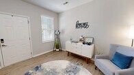 This three-story home in Louisville, Kentucky offers a well-organized layout spread across three distinct levels. The ground floor houses an attached garage with automatic opener, two storage closets, and direct interior access — providing both convenience and practicality. The main living level serves as the heart of the home, featuring two living areas, a kitchen, a half bathroom, and a staircase. The kitchen is outfitted with rich cherry wood cabinetry, granite-style countertops, black appliances, and hardwood-style flooring, with a glass door opening to natural light and outdoor views. The adjacent living areas are bright and welcoming, with light wood-tone floors, neutral walls, and large windows fitted with white blinds that allow natural light to flow freely. The upper floor is dedicated to the two bedrooms and a full bathroom. The generously sized primary bedroom features plush carpeting, multiple windows, and ample natural light. The second bedroom is equally comfortable, also finished with soft carpet and tasteful neutral tones. A compact, elegantly appointed bathroom with a pedestal sink and oval mirror serves the space with clean, minimalist design. Throughout all three levels, the home maintains a cohesive, modern aesthetic with neutral color palettes and functional finishes.