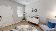 This three-story home in Louisville, Kentucky offers a well-organized layout spread across three distinct levels. The ground floor houses an attached garage with automatic opener, two storage closets, and direct interior access — providing both convenience and practicality. The main living level serves as the heart of the home, featuring two living areas, a kitchen, a half bathroom, and a staircase. The kitchen is outfitted with rich cherry wood cabinetry, granite-style countertops, black appliances, and hardwood-style flooring, with a glass door opening to natural light and outdoor views. The adjacent living areas are bright and welcoming, with light wood-tone floors, neutral walls, and large windows fitted with white blinds that allow natural light to flow freely. The upper floor is dedicated to the two bedrooms and a full bathroom. The generously sized primary bedroom features plush carpeting, multiple windows, and ample natural light. The second bedroom is equally comfortable, also finished with soft carpet and tasteful neutral tones. A compact, elegantly appointed bathroom with a pedestal sink and oval mirror serves the space with clean, minimalist design. Throughout all three levels, the home maintains a cohesive, modern aesthetic with neutral color palettes and functional finishes.