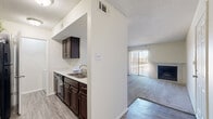 This single-story, 2-bedroom, 1-bathroom residence offers a practical and comfortable layout designed for efficient everyday living. The living room serves as the heart of the home, featuring plush carpeting, a classic wood-burning fireplace, and a sliding glass door with vertical blinds that invites natural light and outdoor access. Adjacent to the living area, the galley-style kitchen is well-equipped with rich dark wood cabinetry, light stone countertops, a tile backsplash, black appliances including a range, microwave, and refrigerator, and wood-look flooring that extends throughout the main areas. A peninsula with a sink opens the kitchen toward the entryway, enhancing the sense of flow. Both bedrooms are carpeted and feature ceiling fans with light fixtures, offering a cozy retreat. Natural light filters in through windows with blinds in each bedroom. The full bathroom includes a dark wood vanity with a single sink, a large mirror with overhead lighting, and wood-look tile flooring. A dedicated laundry room houses a full-size washer and dryer with open shelving above for storage. Two closets provide additional organization throughout the home. Textured ceilings and neutral white walls create a clean, move-in-ready aesthetic throughout.