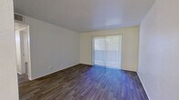 This efficient single-floor, one-bedroom, one-bathroom unit is thoughtfully laid out to make the most of its compact footprint. The living room serves as the heart of the space, featuring durable wood-style plank flooring, neutral cream-toned walls, and a large sliding glass door dressed with vertical blinds that allows natural light to fill the room and provides an outdoor connection.

The galley-style kitchen is neatly arranged with white cabinetry, speckled stone countertops, a stainless steel sink, and black appliances including a gas range and full-size refrigerator. A door at the end of the kitchen leads to additional access within the unit.

The bedroom is a comfortable, well-proportioned room finished with plush carpet, a ceiling fan, a window with horizontal blinds for natural light and privacy, and a closet with a paneled door for ample storage.

The bathroom is clean and functional, featuring a full-size soaking tub and shower combination with white subway tile surround, brushed nickel fixtures, and a toilet. The space is completed by a hallway and entrance area that connect the rooms efficiently. Throughout the unit, the light color palette and consistent finishes create a cohesive, move-in-ready atmosphere.