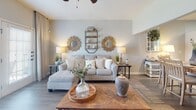 Located at 5402 FM-1488 in Magnolia, Texas, this single-story home offers a well-designed open-concept floor plan that seamlessly connects the kitchen, dining, and living areas. The kitchen is appointed with crisp white cabinetry featuring matte black hardware, granite countertops, stainless steel appliances including a dishwasher, and a functional breakfast bar with barstool seating — ideal for casual dining or entertaining. The adjoining dining area provides dedicated space for a full dining table and flows naturally into the living room, which boasts vaulted ceilings, a ceiling fan, hardwood-style flooring, and large windows with access to the outdoors, allowing for abundant natural light. Track lighting accents the dining space, adding a modern touch. The bedrooms are carpeted for comfort and feature closets and windows with natural light. The bathroom includes granite countertops, white cabinetry with modern hardware, and hardwood-style flooring, maintaining a consistent aesthetic throughout the home. Neutral gray tones on the walls complement the warm wood floors, creating a cohesive and welcoming ambiance across the entire residence.