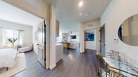 Located at 7701 Interbay Blvd in Tampa's 33616 zip code, this single-floor residence offers a thoughtfully designed open-concept layout with contemporary finishes throughout. Dark wood-style flooring runs continuously across the living areas, creating a cohesive and polished aesthetic. The entryway provides a welcoming introduction to the space, opening toward a well-appointed kitchen and a bright living area beyond. The kitchen features light wood cabinetry, a white subway tile backsplash, stainless steel appliances including a French door refrigerator, electric range, microwave, and dishwasher, along with a built-in pantry for additional storage. The open living and dining area is bathed in natural light from multiple windows dressed with blinds and sheer curtains, and is anchored by a ceiling fan overhead. The bedrooms offer a calm, neutral palette with ample natural light from well-placed windows. The primary bedroom includes distinctive wall décor and generous space for furnishings. Two bathrooms serve the residence — one featuring a granite-topped vanity with modern cabinetry, and the other offering a full tub-shower combination with large-format tile surround. Throughout, matte black hardware and clean architectural lines lend the home a modern, cohesive character.