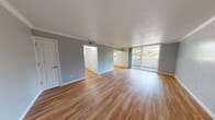 This well-appointed single-floor residence offers a thoughtfully designed layout that balances open communal spaces with comfortable private areas. The spacious living and dining area is finished with light hardwood flooring and neutral gray walls, creating a bright and airy atmosphere. Crown molding adds a refined architectural detail throughout the main living spaces. Large sliding glass doors open directly onto a private outdoor balcony, flooding the interior with natural light and offering serene views of surrounding mature trees.

The kitchen is fully equipped with warm wood cabinetry, granite-style countertops, and a complete suite of stainless steel appliances, including a refrigerator, range, microwave, and dishwasher. A window above the kitchen area provides additional natural light and continued views of the tree-lined surroundings.

The bedrooms are carpeted for comfort and painted in soft gray tones, contributing to a calm and restful environment. Each bedroom features ample closet space, with at least one room showcasing full mirrored sliding closet doors. Windows in the bedrooms invite in natural light and maintain the connection to the verdant outdoor setting.

Throughout the residence, consistent finishes — including hardwood-style flooring in common areas, clean white trim, and neutral wall tones — create a cohesive and move-in-ready aesthetic.