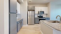 Located at 18313 FM 1093 in Richmond, TX, this single-story, one-bedroom, one-bathroom unit offers a thoughtfully designed layout with modern finishes throughout. Light-toned wood-look flooring flows consistently across the entire space, creating a clean, cohesive aesthetic.

The kitchen is a standout feature, equipped with stainless steel appliances — including a refrigerator, electric range, and over-the-range microwave — complemented by granite countertops, a white subway tile backsplash, and a two-tone cabinet design combining crisp white upper cabinets with slate-gray lower cabinets.

The bedroom is a comfortable, well-lit retreat featuring dual windows with white horizontal blinds that allow natural light to fill the room, along with a ceiling fan for added comfort. The room provides direct access to the bathroom and a dedicated closet, offering convenient and functional connectivity.

The bathroom continues the modern theme with gray cabinetry, granite countertops, a large vanity mirror, and updated fixtures. Light-toned flooring carries through here as well, maintaining visual consistency throughout the unit.

Neutral, warm-toned walls throughout the space contribute to an open, inviting atmosphere, while the efficient and well-organized floor plan ensures every square foot is purposefully utilized.