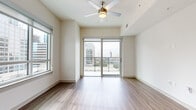 Located in the heart of Uptown Charlotte on W Martin Luther King Jr Blvd, this modern single-floor residence offers a thoughtfully designed layout with stylish finishes throughout. The bright and airy living area features rich wood-style flooring, a ceiling fan, and large sliding glass doors that open onto a private balcony with striking views of the Charlotte city skyline. Natural light fills the space through multiple windows framing dynamic urban vistas.

The contemporary kitchen is outfitted with light wood flat-front cabinetry extending to the ceiling, a horizontal tile backsplash, white quartz countertops, a matte black sink fixture, and a full suite of stainless steel appliances including a refrigerator, range, microwave, and dishwasher. Recessed lighting and wood-style flooring carry through the kitchen and hallway.

The carpeted bedrooms are generously proportioned, each benefiting from large windows that capture sweeping views of the surrounding skyline and cityscape. The bathroom is finished with light ceramic tile flooring, a modern vanity, and a glass-enclosed walk-in shower with tile surround. Clean white walls and neutral tones throughout give the residence a cohesive, contemporary feel well-suited to urban living.