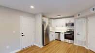 Located at 1500 Champion Pines Ln in Augusta, Georgia, this well-designed one-bedroom, one-bathroom unit offers a practical and modern living experience on a single floor. The open kitchen and living area serves as the heart of the home, featuring crisp white shaker cabinetry with matte black hardware, light quartz countertops, a subway tile backsplash, and a full suite of stainless steel appliances including a refrigerator, range, microwave, and dishwasher. Light hardwood-style flooring runs throughout the main living areas, lending warmth and continuity to the space. The living room is bright and airy, benefiting from recessed lighting and a set of French doors that invite natural light and provide access to the outdoors. The bedroom offers plush carpeting underfoot, a ceiling fan with light fixture, and a window with outdoor views, creating a comfortable and restful retreat. A dedicated closet provides convenient storage. The bathroom is finished with clean white vertical tile surrounding a soaking tub, complemented by oil-rubbed bronze fixtures for a refined touch. Neutral wall tones throughout unify the space with a calm, cohesive aesthetic.