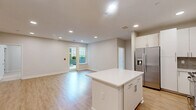 This well-appointed 2-bedroom, 2-bathroom residence at 114 Forrest Ave in Narberth, PA offers a thoughtfully designed single-floor layout. The open-concept kitchen and living area serves as the heart of the home, showcasing white shaker cabinetry, a gray subway tile backsplash, stainless steel appliances including a gas range, dishwasher, and French door refrigerator, and a central island with a clean white countertop — ideal for both meal prep and casual dining. Light-toned hardwood-style flooring flows throughout the main living areas, complemented by recessed lighting that creates a bright, airy atmosphere. The living room features direct access to a private outdoor area overlooking a beautifully landscaped courtyard with modern planters and greenery. Both bedrooms are finished with plush carpet and receive natural light through generous windows. The primary bedroom includes a walk-in closet with custom built-in shelving and a well-sized en-suite bathroom featuring a double-sink vanity with warm wood cabinetry and large-format tile flooring. Additional highlights include three closets, a dedicated laundry room, a dining area, and a utility room, providing ample storage and functionality throughout.