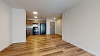 Located at 1326 E Washington Ave in Madison, Wisconsin, this single-floor unit offers a well-designed, functional layout with consistent finishes throughout. The open-concept living and kitchen area is anchored by warm hardwood-style flooring and recessed lighting, creating a bright and welcoming atmosphere. The kitchen is equipped with medium-toned wood cabinetry offering ample storage, gray laminate countertops, a double sink, and black appliances including a refrigerator, electric range, and dishwasher — all set atop light hardwood-style flooring.

The living area is generously proportioned, providing flexible space for various furniture arrangements, and features a large window with vertical blinds that allows natural light to fill the room. The bedroom is carpeted in a neutral tone, offering a comfortable contrast to the hard flooring elsewhere, and includes a window for additional natural light.

The bathroom features hardwood-style flooring, a dark wood vanity with a white countertop, a wall-mounted mirror, and clean neutral walls. A dedicated laundry area houses a full-size front-loading Whirlpool washer and dryer with wire shelving above for added storage convenience.