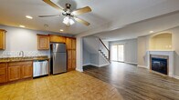 Located at 7203 NE 47th Terr in Kansas City, MO, this two-story home offers a well-organized layout across two levels with a variety of functional and comfortable spaces. The main floor opens with a tiled entryway corridor leading into a bright, open-concept living and kitchen area. The living room features warm hardwood-style plank flooring, a classic fireplace with a white mantel and arched niche above, and a sliding glass door that allows natural light to fill the space. A ceiling fan adds to the room's comfort. The kitchen is equipped with warm-toned wood cabinetry, granite-style countertops, a white subway tile backsplash, and a full suite of stainless steel appliances including a refrigerator, range, microwave, and dishwasher. Tile flooring flows throughout the kitchen and entry areas. A dedicated laundry room with tile flooring and washer/dryer hookups is conveniently located on the main level. The upper floor features carpeted bedrooms with neutral gray walls, ample closet space, and windows that bring in natural light. A bathroom includes a wood-toned vanity with a white countertop and tile flooring. The attached garage provides additional utility and storage space, completing this practical and move-in-ready home.